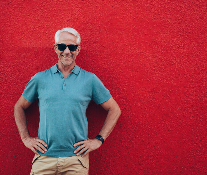 smiling man in front of red wall