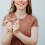 woman holding invisalign clear aligners to answer invisalign questions