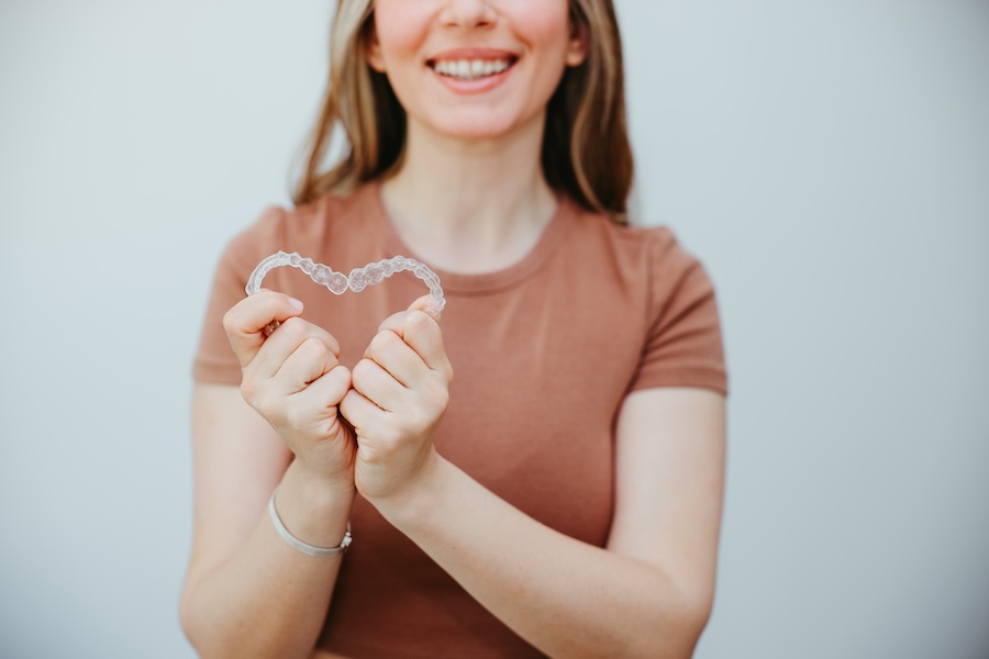 woman holding invisalign clear aligners to answer invisalign questions